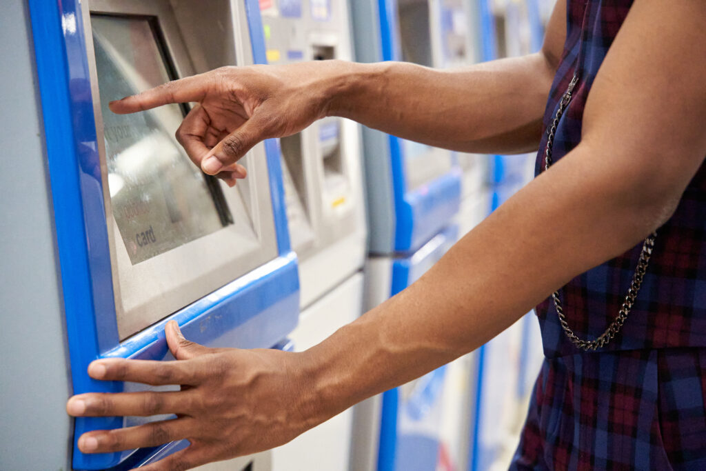 zeigt Mann an Kartenautomaten ATM